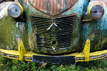 Fototapeta na wymiar Front eines Auto Oldtimer Citroen 2CV grau beige blau schwarz alt grunge zerkratzt schmutzig rostig vintage farbig lackiert