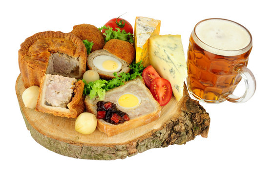 Traditional ploughman's buffet lunch ingredients with a pint of beer isolated on a white background