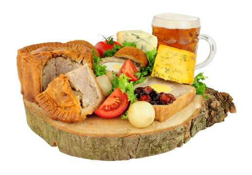 Traditional ploughman's buffet lunch ingredients with a pint of beer isolated on a white background