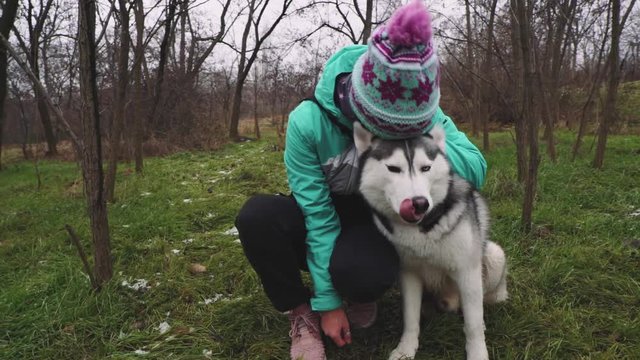 Young beautiful woman walks and plays with her Husky dog at winter around forest