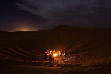 people sitting around a fire in the Sahara desert at night