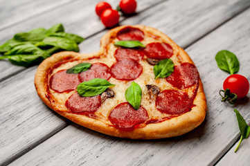 Pizza in the shape of a heart on a wooden table background. The concept of romantic love for Valentine's Day
