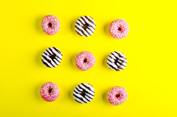 Colorful tasty donuts on yellow background. Flat lay, top view. 
