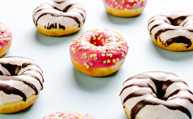 Donut with pink icing and star sprinkles on the top on blue background. Selective focus.