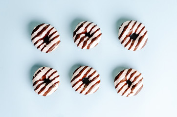 Donuts wit white and dark chocolate on top on a blue background. Top view. Flat lay.