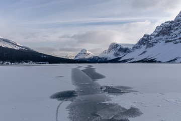 Bow Lake Banff Canada during the winter season. First snow at a glacial lake located in the Rocky Mountains. Winter wonderland at the lake with mountain background. 