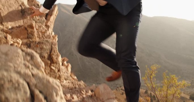 Confident multiethnic businessman climbing up the steep cliff, wearing white collar - way to success concept 4k