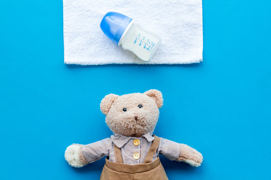 Handmade toys for newborn baby. Teddy bear. Feeding bottle with milk. Blue background top view