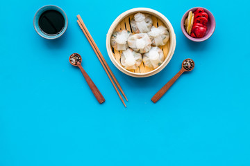 Chinese food set with dim sum, sticks, spices and tea on blue background top view copy space