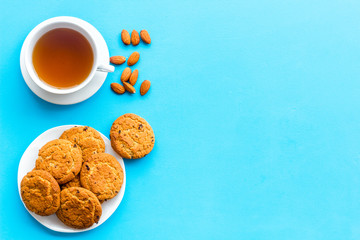 Dessert for evening tea. Cup of tea, fresh homemade cookies on blue background top view space for text