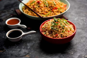 Schezwan veg noodles is a spicy and tasty stir fried flat Hakka noodles with sauce and veggies. served with chopsticks. selective focus