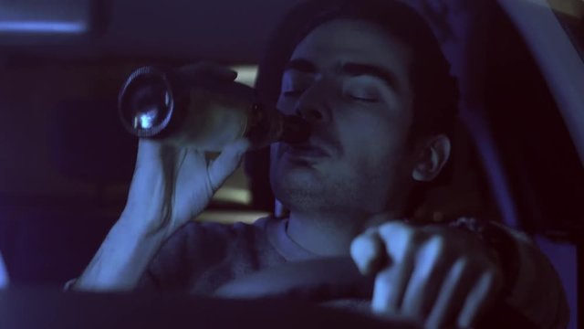 Drunk driver drinking in his car a beer bottle.