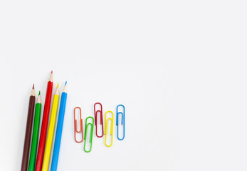 School supplies stationery concepts, Multi-colored pencils and clips on white background with copy space. View from above.