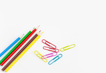 Stationery office supplies concept, Colored crayon pencils with colorful clips on white background with copy space. Top view.