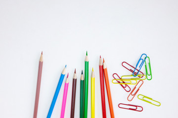 Office supplies concepts, Colored crayon pencils and clips on white background with wide banner, brochure, poster design template with copy space. Top view, Closeup.