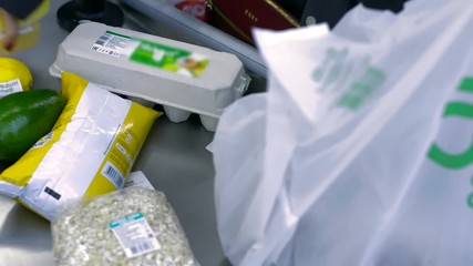 upper view different fresh food products on conveyor belt and white plastic bag at cashier desk in modern supermarket