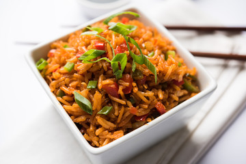 Schezwan Fried Rice Masala is a popular indo-chinese food served in a plate or bowl with chopsticks. selective focus