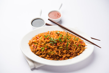 Schezwan Fried Rice Masala is a popular indo-chinese food served in a plate or bowl with chopsticks. selective focus