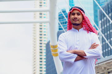 Muslim  Arab man.He is smile and cross one’s arm.He is standing in town. Photo concept Arab man and portrait.