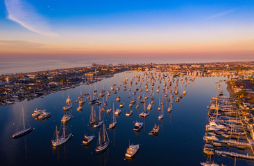 Drone shot of Newport Beach harbor in Orange County, California early in the morning with boats below. - Powered by Adobe