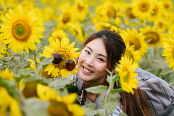 Beauty joyful teenage girl with sunflower enjoying nature and laughing on summer sunflower field. 