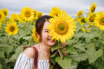 Beauty joyful teenage girl with sunflower enjoying nature and laughing on summer sunflower field. 