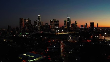 Drone shot from above of downtown Los Angeles skyline in California after sunset during orange twilight sky on a beautiful evening.