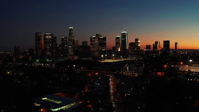 Drone shot from above of downtown Los Angeles skyline in California after sunset during orange twilight sky on a beautiful evening.