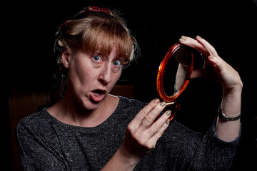 Woman with hair curlers and with funny emotion on the face. Dark key