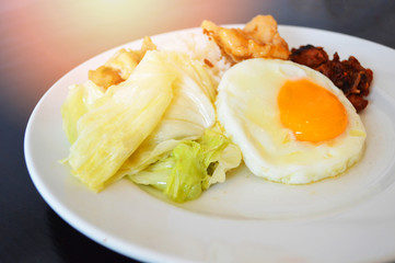 Breakfast egg fried chicken with cabbage vegetable and on rice white plate