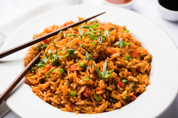 Schezwan Fried Rice Masala is a popular indo-chinese food served in a plate or bowl with chopsticks. selective focus