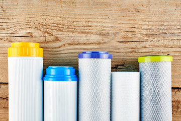 Water filters. Carbon cartridges on a wooden background. Household filtration system.
