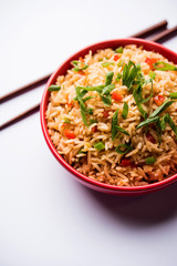 Schezwan Fried Rice Masala is a popular indo-chinese food served in a plate or bowl with chopsticks. selective focus