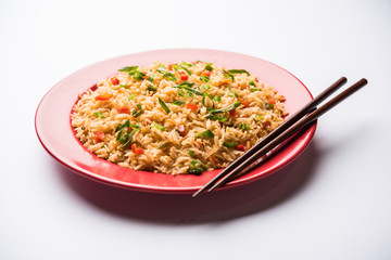 Schezwan Fried Rice Masala is a popular indo-chinese food served in a plate or bowl with chopsticks. selective focus