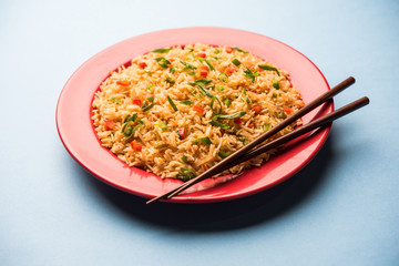 Schezwan Fried Rice Masala is a popular indo-chinese food served in a plate or bowl with chopsticks. selective focus