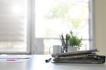 Paper document files and pen business equipment on office table and window light.