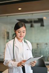 Fototapeta na wymiar Asian female doctor holding digital tablet. Medicine and health care concept - Image
