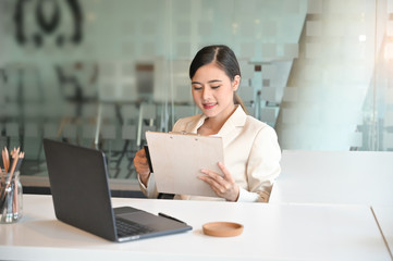 Business woman reading a document report on office workplace.