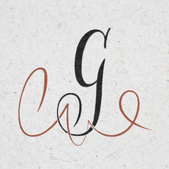 Calligraphic letter G with flourishes on kraft paper
