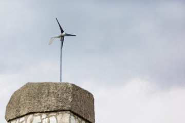 Wind electric generator weather vane on cloudy sky background.