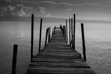 Fototapeta premium Czarna Biała Monochromatyczna stara drewniana mosta krzyża ścieżka morze. Koncepcja samotnego smutku prowadzi donikąd bez celu i nikt nie pomaga prowadzić