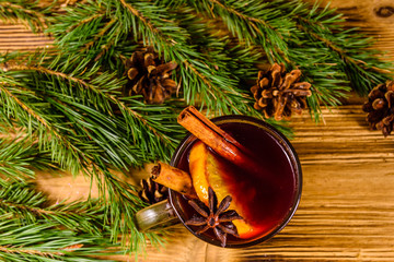 Cup of mulled wine with cinnamon and fir tree branches on wooden table. Top view