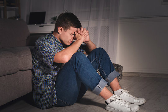 Desperate Teen Boy In Dark Room At Home