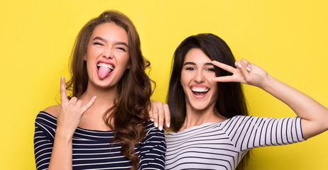 Carefree women fooling around together on yellow background