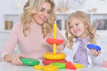 Close up portrait of young woman and little girl playing with educational toy