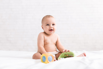Fototapeta na wymiar Cute newborn baby playing with toys on bed