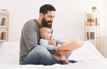Father reading book to little baby son