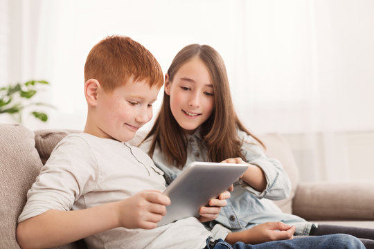 Happy siblings playing with pc tablet together