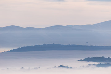 Fog filling a valley in Umbria (Italy), with layers of mountains and hills and various shades of blue