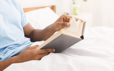 Black man studying business literature in bed